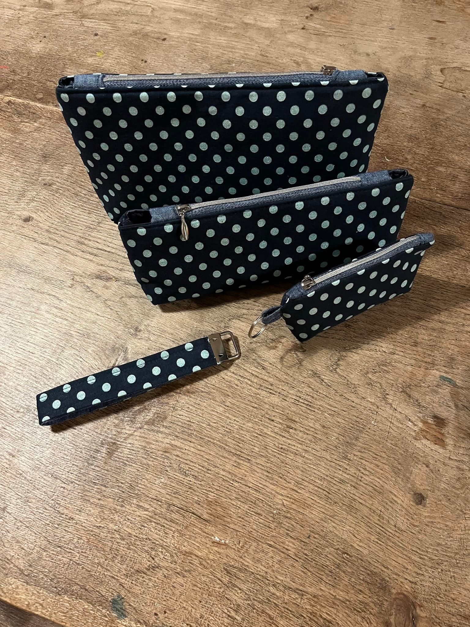Set of black pouches with white polka dots on a wooden surface