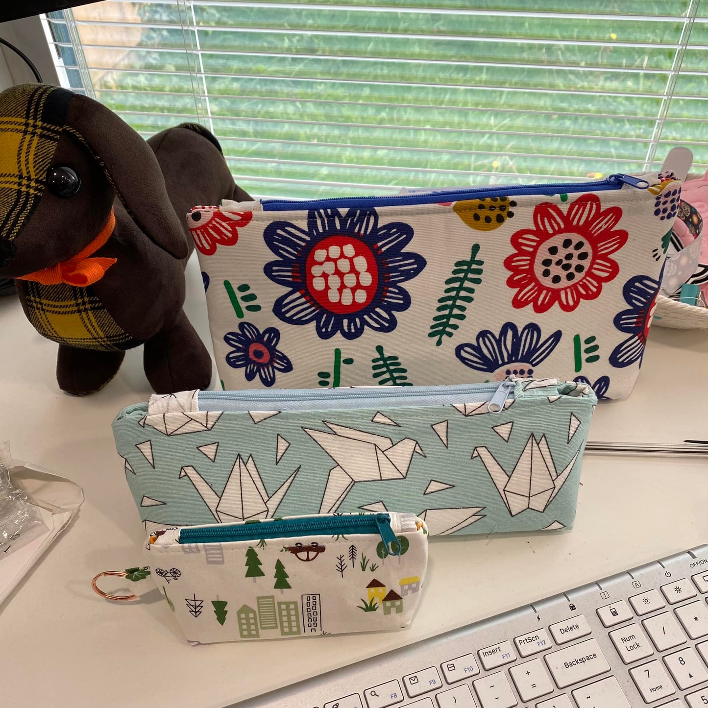Three fabric pouches with different patterns on a desk.