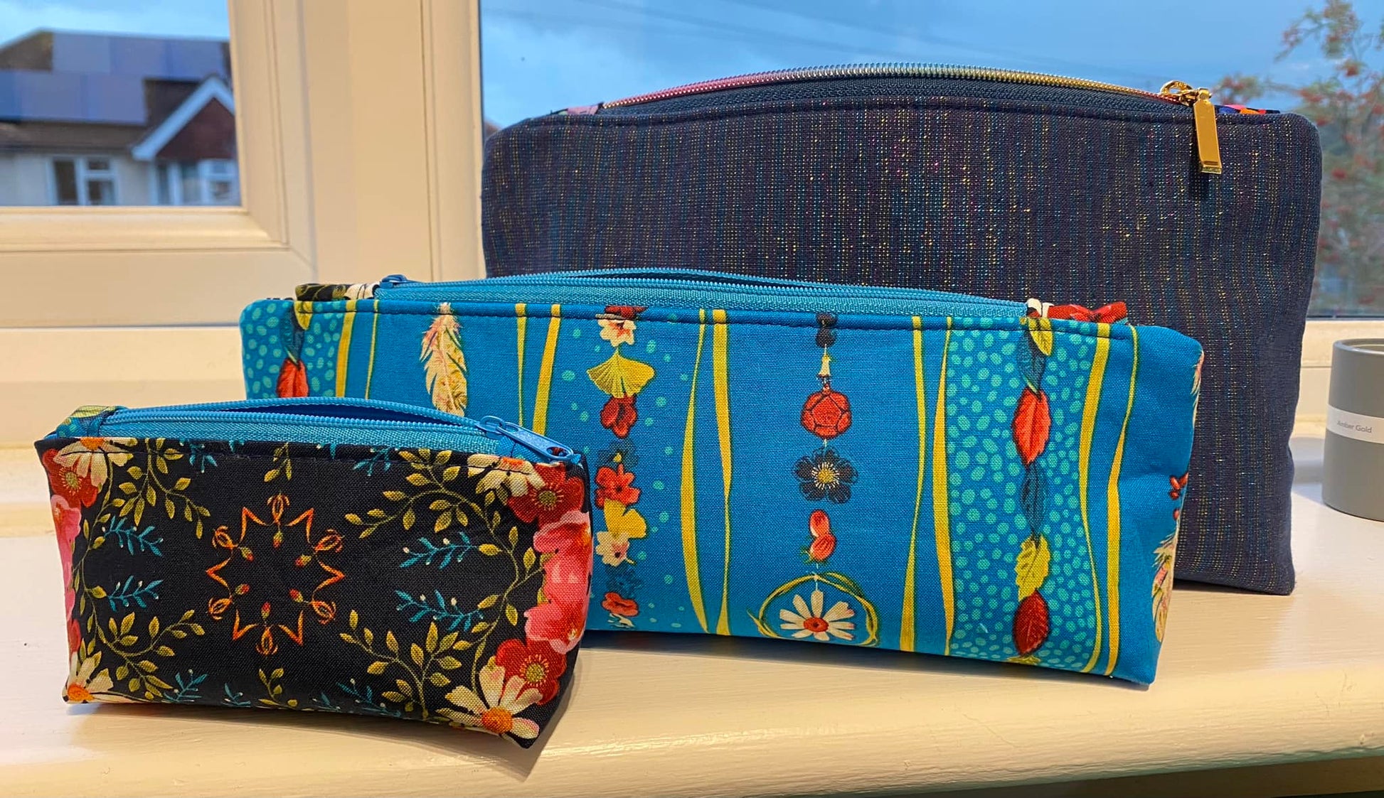 Three fabric pouches of different sizes on a windowsill.