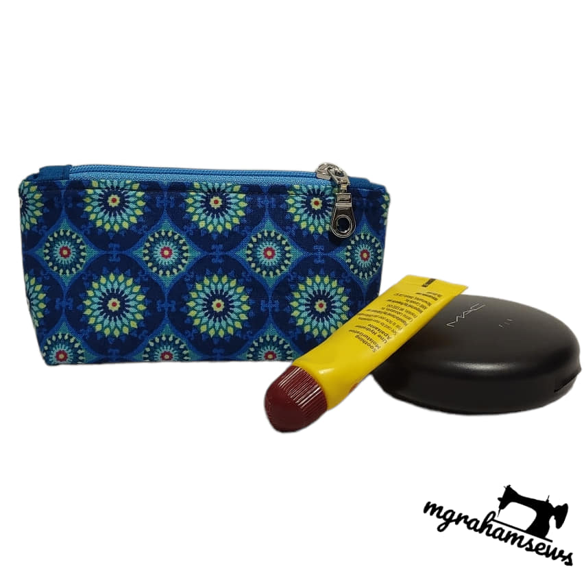 Blue patterned pouch with a yellow and red item and a black object on a white background, branded 'mghamsews'.