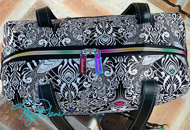 Top view of the Brooklyn Bag from Swoon Sewing Patterns, made by Kimberly Cummins from MyDani Bags in Tula Pink fabric with black vinyl accents and rainbow coloured hardware