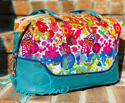 Brooklyn Bag from Swoon Sewing Patterns, made by Kimberly Cummins from MyDani Bags in Alison Glass fabric with teal vinyl accents, blue piping, and rose gold hardware